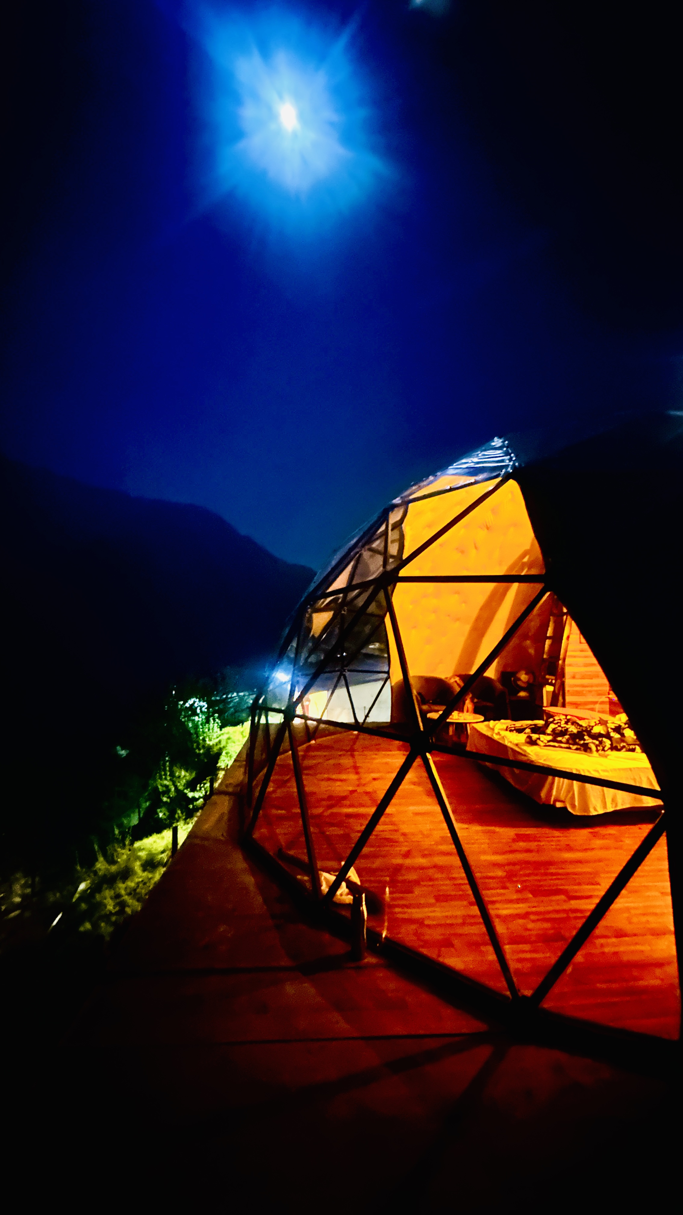 Dome House glowing at night under a full moon in Auli